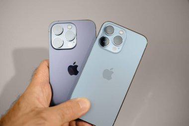 Paris, Fransa - Sep 29, 2023: Bir el Apple Bilgisayarları 'ndan gelen akıllı telefonları gri arka planda tutuyor. Mobil teknoloji ve tarzın örneğini deneyimleyin