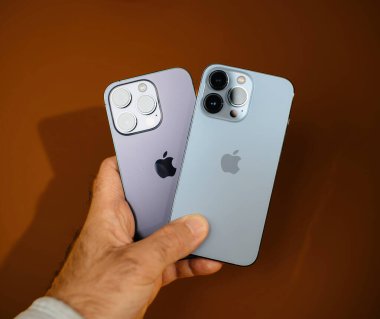 Paris, Fransa - Sep 29, 2023: Bir kişi iPhone 14 Pro ve 15 Pro 'yu karşılaştırır, her ikisini de elinde tutarak, arkaplandaki farklılıkları vurgular