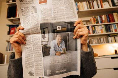 Frankfurt, Almanya - 20 Aralık 2023: Bir kadın, Vitose raflarıyla bir oturma odasında George Clooney 'nin oynadığı Nespresso reklamını çekiyor