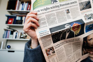 Frankfurt, Almanya - 20 Aralık 2023: Financial Times 'ın Batı ülkeleriyle ilgili haberleri, Rusya' nın mal varlığına el koymayı ve Çin 'deki siyasi oyunları ele geçirmeyi düşünen bir kadın tarafından okunuyor