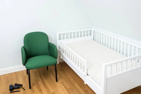 Simple Nursery Room Featuring White Crib Green Chair Plain Background — Stock Photo, Image