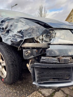 Ağır hasar görmüş bir arabanın ön görüntüsü, bir kaza ya da çarpışmadan kaynaklanan geniş çaplı tahribatı ortaya çıkarıyor.