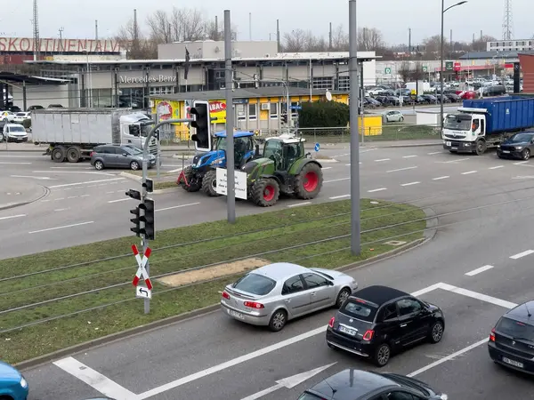 キール ドイツ 2024年6月9日 一つの緑色のトラクターが夜のセットとして都市道路の車やトラックの忙しい流れの中で際立っています — ストック写真