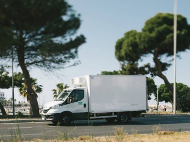 Mallorca, İspanya - 27 Haziran 2023: Beyaz bir Iveco soğutmalı yarı kamyonet Av 'da hızla ilerliyor. Cebrail Roca, arka plandaki yat limanını gösteren eğimli bir mercekle yakalandı..