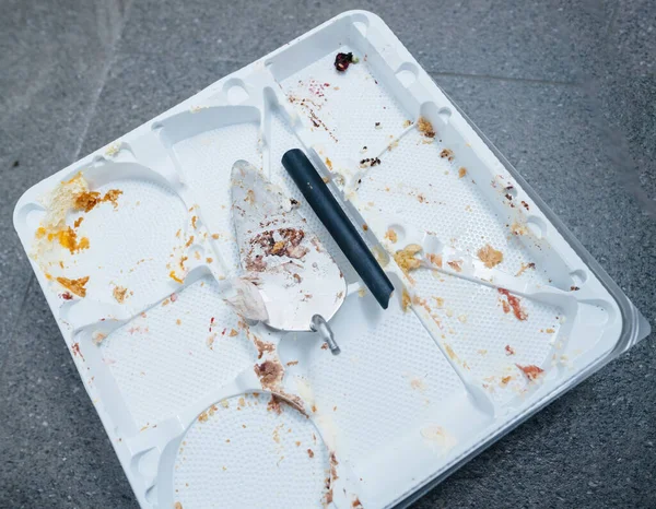 壊れたスパチュラだけが空のプラスチック製のケーキトレイの上に残るように侵入は アフターパーティーの残骸の中で展開されます — ストック写真