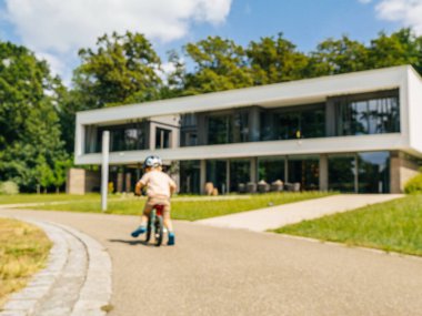 Bisiklet süren bir çocuğa odaklanan bu bulanık görüntü genç hareketinin özünü yakalıyor zarif, modern bir villa arka planına karşı.