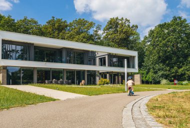 Bir çocuğun park yolunda bisiklet sürüşünü net bir şekilde görebiliyoruz. Bir villanın modern mimarisi çarpıcı bir arka plan sağlıyor.