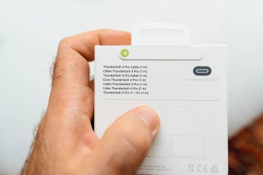 Paris, Fransa - 3 Kasım 2023: Elma Yıldırımı 4 Pro kablo, 1 metre uzunluğunda, erkek eli, Apple 'ın en pahalı bilgisayar aksesuarlarından biri olarak tanınıyor.