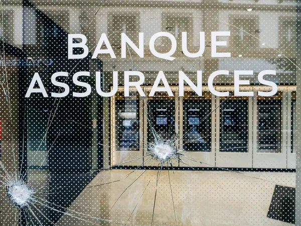 bank branch, with text in French Bank and Insurance with its glass shattered following a protest in France, highlighting the aftermath of the demonstration