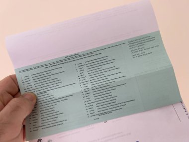 Birinci şahıs bakış açısına göre, bir erkek el, Fransız arabaları için özel talimatlarla sertifika sertifikası ve sigorta sertifikası sergileyen bir erkeğin yakın çekimini tutar.