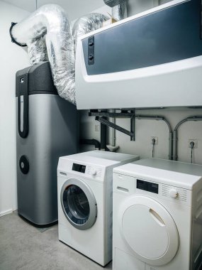 Modern çamaşır makinesi, kurutma makinesi ve modern havalandırma sistemiyle donatılmış konut çamaşır odası.