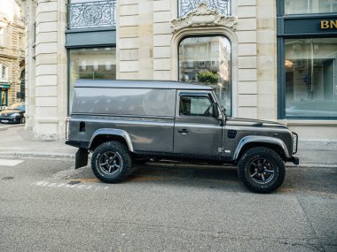 Strasbourg, Fransa - 2 Temmuz 2023: Klasik Land Rover Defender arka planda tarihi binalar bulunan bir Avrupa kentsel caddesine park etti.