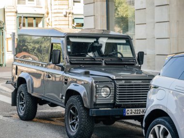Strasbourg, Fransa - 2 Temmuz 2023: Klasik Land Rover Defender arka planda tarihi binalar bulunan bir Avrupa kentsel caddesine park etti.