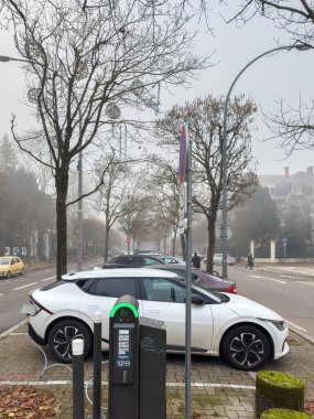 Strasbourg, Fransa - 7 Aralık 2023: Sisli bir günde şehir merkezindeki bir araba şarj parkının manzarası yükseldi ve arka planda birden fazla araba arasında bir Kia arabası yer aldı.
