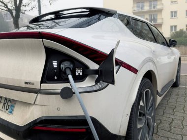 Strasbourg, Fransa - 7 Aralık 2023: Arka planda apartman binaları bulunan ve çevre dostu, bir gecede şarj edilen elektrikli bir Kia arabasının yan görüntüsü