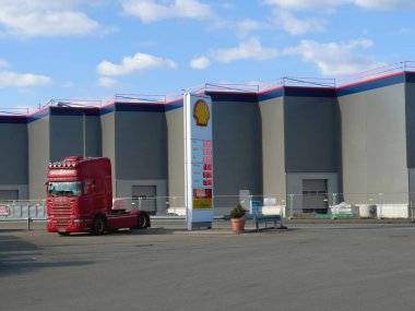 Hamburg, Almanya - 26 Şubat 2022: Shell benzin istasyonuna yakın park etmiş İskandinav R500 kamyonunun görüntüsü ve arka planda büyük bir depo taşımacılık dağıtım binası