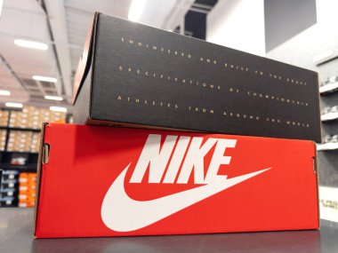 Fransa - 12 Ekim 2023: Nike ikonik ayakkabılar, canlı kırmızı kartonla paketlenmiş, alışverişçiler yeni ayakkabılar ararken. Yukarıda, başka bir kutu gururla sloganlar sergiliyor