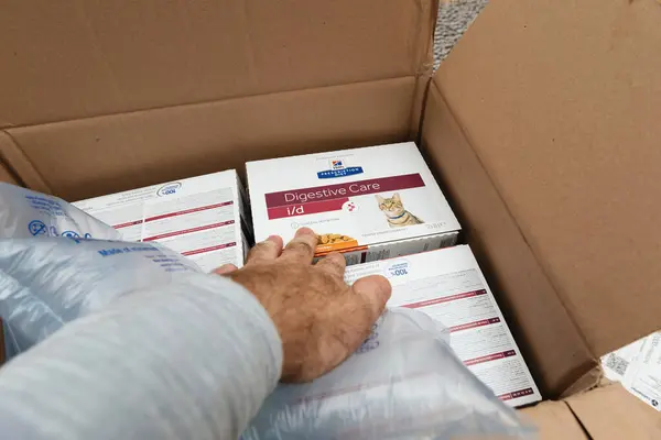 ドイツのブレーメン 10月 2023 それは慎重に複数のパッケージをアンボックスとして男性の手 ヒルズ処方ダイエット消化ケアI 消化問題の猫のために調整された特別な専用食品 ロイヤリティフリーのストック写真