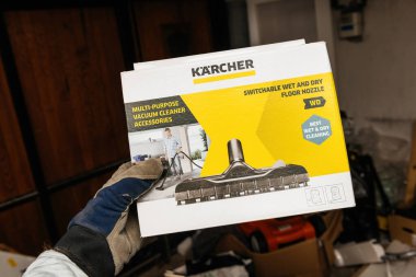 Bremen, Almanya 10 Aralık 2023: Bir erkek eli, Karcher 'ın çok amaçlı ıslak ve kuru zemin başlığını kirli bir garajda, çok amaçlı temizlik görevlerine hazır bir şekilde tutuyor.