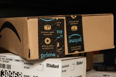 Bremen, Germany - Dec 10, 2023: hero object is a new Amazon Prime cardboard package above the Vaillant VR 920 Internet connection device for gas boilers, promising enhanced connectivity and control. clipart
