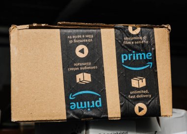 Bremen, Almanya - 10 Aralık 2023: Bir depo arkaplanına karşı bir Amazon Prime karton paketi, Birincil Üyeliğin yararlarını vurgulayan Sınırsız Hızlı Teslimat yazısını sergiliyor