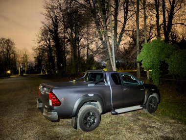 Paris, Fransa - 26 Aralık 2023: Moda fotoğrafçılığında büyüleyici bir sahne yaratan şık bir Toyota Hilux SUV gecenin karanlığında park halindedir..