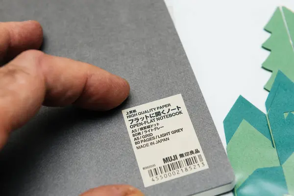 2023年12月10日 德国不来梅 一只雄性手打开了日本最新的生态友好型电子商务订单 Mujis Light Ray Planner 日本产高质量的纸 为便于使用而平开 — 图库照片