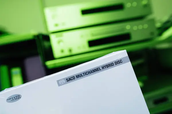 ハイデフジャズミュージックをフィーチャーした新しいSacdのパッケージは バックドロップに欠陥のあるハイファイオーディオファイルシステムを備えた鮮やかな緑の背景で展示されています — ストック写真