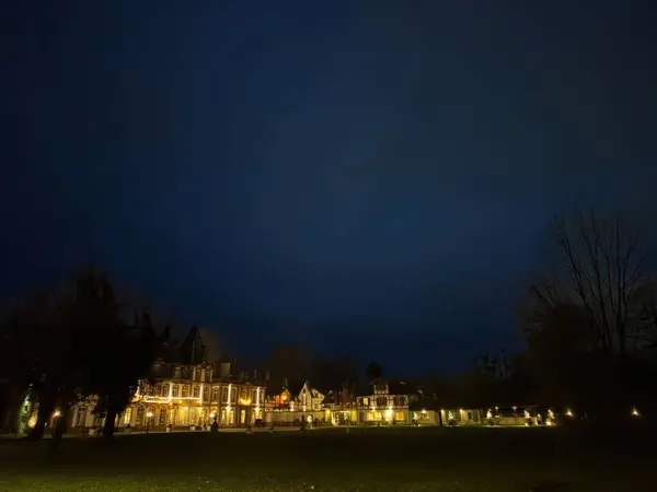 夕暮れの空に照らされたビクトリア様式の邸宅で 不動産の敷地内を照らす灯り — ストック写真