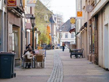 Haguenau, Fransa - 20 Mart 2024: Açık hava oturma ve klasik sokak lambalarıyla sakin bir Avrupa sokağı, huzurlu bir günlük hayatı çağrıştırıyor - Haguenau