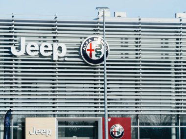 Strasbourg, France - Mar 20, 2024: A bustling Jeep And Alfa Romeo dealership with a prominent sign displayed on the side, attracting customers with its wide selection of vehicles. clipart