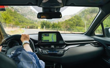Mallorca, İspanya - 28 Haziran 2023: POV - Bir eli Apple Bilgisayarlı bir araba kullanan bir kadın Navigasyon için GPS kontrol paneli olarak Carplay