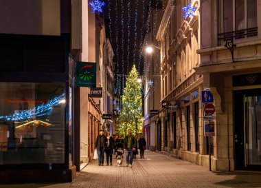 Strasbourg, Fransa - 23 Aralık 2023: Strasbourgs yayalar tatil ışıklarıyla parıldıyor, yerel halk yüksek bir Noel ağacının altında geziniyor, mevsimsel keyfi kucaklıyor