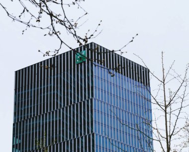 Frankfurt, Almanya - 31 Aralık 2024: Frankfurt 'taki BNP Paribas Merkez Bankası' nın düşük açılı görüntüsü, bahar dallarından gizlice bakmak, büyüme ve istikrarı sembolize ediyor