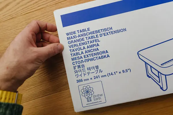フランス 2024年3月9日 ブルーストライプのブラザーのロゴに焦点を当てた縫製テーブルボックスを保持する男性の手のクローズアップ 多言語の説明をフィーチャー — ストック写真