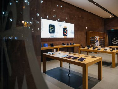 Paris, France - Dec 23, 2023: The calm of an empty Apple Store, products lined up neatly, with a promo sign for the holidays and large banners for the Apple Watch smartwatch iOT clipart