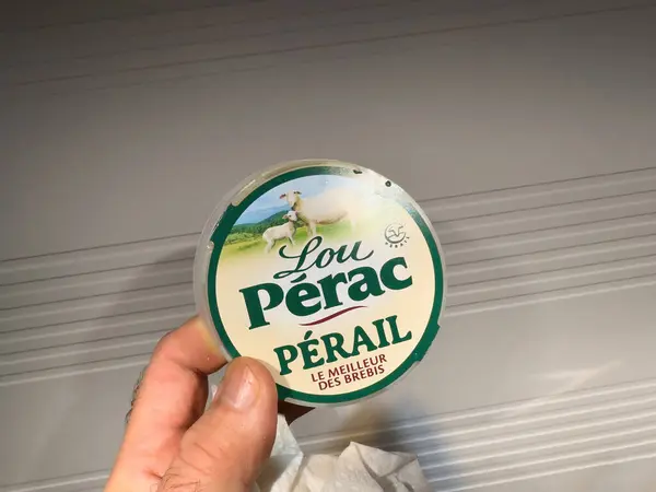 stock image Paris, France - Mar 8, 2024: Personal perspective - hand presents a round package of Lou Perac Perail sheep cheese, emphasizing quality dairy produce.