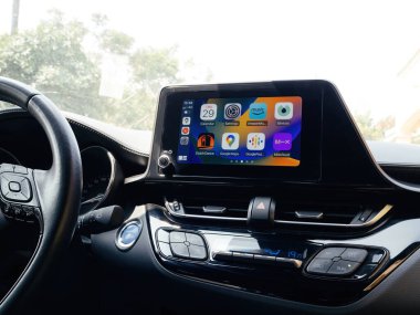 Mallorca, Spain - Jun 29, 2023: Interior of a car showing the steering wheel and a dashboard screen with Apple CarPlay activated showing apps icons clipart