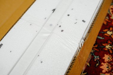 İçinde stiroköpük korumalı bir nesne bulunan karton bir kutu, güvenli taşımayı sağlamak için kullanılan paketleme detaylarını ve koruyucu materyalleri gösterir.
