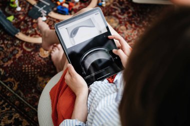 Londra, Birleşik Krallık - 11 Haziran 2023: Konforlu bir oturma odasında, bir kadın iPad Pro 'sunda Apple Vision Pro karışık gerçeklik kulaklığının anahtar özelliklerini keşfeder.