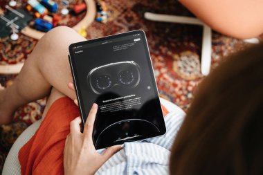 Londra, Birleşik Krallık - 11 Haziran 2023: Bir kadın, iPad Pro 'sunda, rahat bir oturma odasında Apple Vision Pro karışık gerçeklik kulaklığına bakıyor.