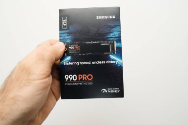 Paris, Fransa - 4 Mar 2024: Bir erkek el 4TB NVMe SSD disk tutuyor, özellikle Samsung Pro 990, büyük bir depolama kapasitesi sergiliyor, beyaz bir arka plana karşı boks olmayan bir senaryoda