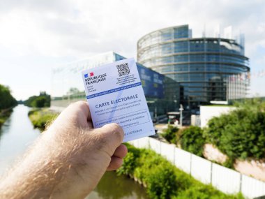 Strasbourg, Fransa - 6 Haziran 2024: Strasbourg 'daki Avrupa Parlamentosu binası önünde elinde QR kodu bulunan bir Fransız seçim kartı tutan kişi,