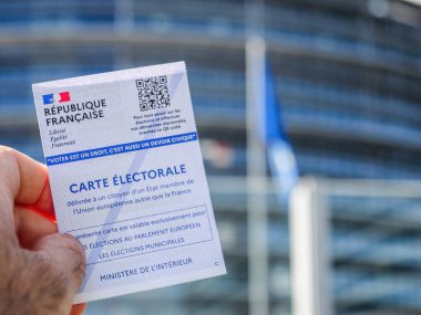 Strasbourg, Fransa - 6 Haziran 2024: Strasbourg 'daki Avrupa Parlamentosu binası önünde elinde QR kodu bulunan bir Fransız seçim kartı tutan bir kişi, 2024 AB' nin önemini vurguladı