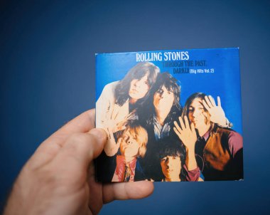 Paris, Fransa - 6 Nisan 2024: Rolling Stones through the past, Darkly Big Hits Vol 'un SACD' sini tutan bir erkek. 2, mavi arkaplan karşısında, albüm kapağı ve ayrıntıları gösteriliyor