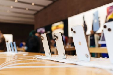 Paris, Fransa - 28 Ekim 2022: Arka planda müşteri siluetleri ve kalabalık bir Apple mağazasının duvarında büyük bir reklam olan Apple bilgisayarları ve iPhone dizileri