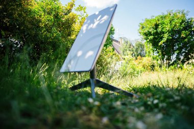 Frankfurt, Almanya - 15 Haziran 2023: SpaceX uydu anteninin arka planda bir evle birlikte bahçeye kurduğu bir Starlink 'e odaklı olmayan bir bakış, modern teknolojinin entegrasyonunu vurguluyor