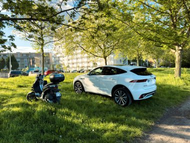 Strasbourg, Fransa - 23 Nisan 2024: Bir Fransız HLM apartmanı önünde lüks bir elektrikli jaguar E-Pace SUV 'nin yanına park edilmiş bir motosiklet, modern lüks ve lüks arasındaki zıtlığı vurguluyor