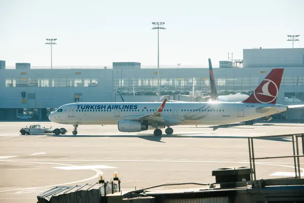 stock image Basel, Switzerland - Oct 2, 2015: Turkish Airlines Airbus a321 TC-JSH aircraft being towed on the tarmac at an airport, with the terminal building in the background, highlighting airport ground