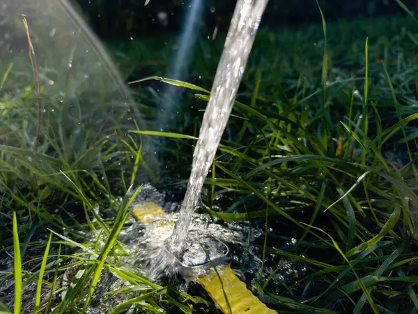 stock image Paris, France - Sep 23, 2022: An Apple Watch Ultra 2 lying in the grass with water pouring over it, showcasing its durability and water resistance, surrounded by lush green blades and sunlight